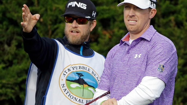 Hunter Mahan, right, listens to his caddie John Wood on...