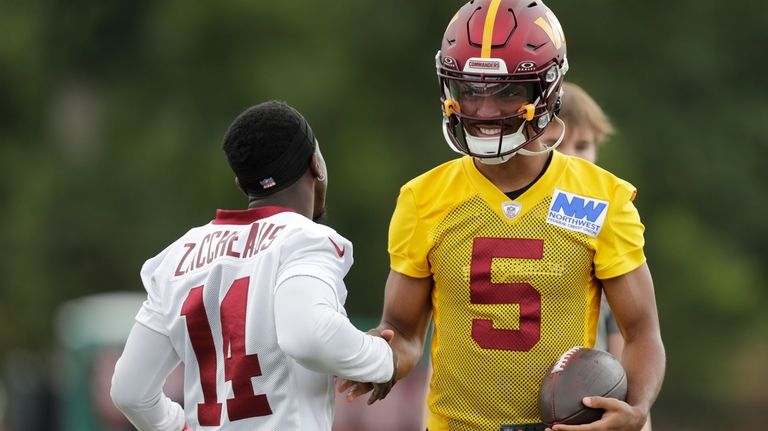 Washington Commanders quarterback Jayden Daniels (5) greets wide receiver Olamide...