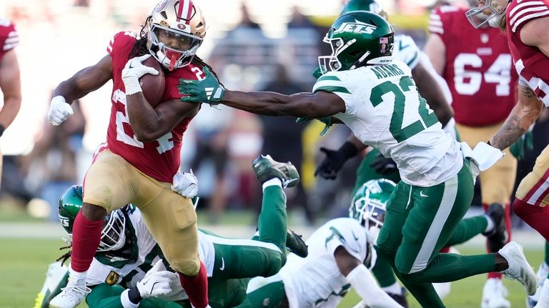 San Francisco 49ers running back Jordan Mason, left, runs against...