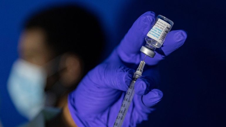 A family nurse practitioner prepares a syringe with mpox vaccine before...