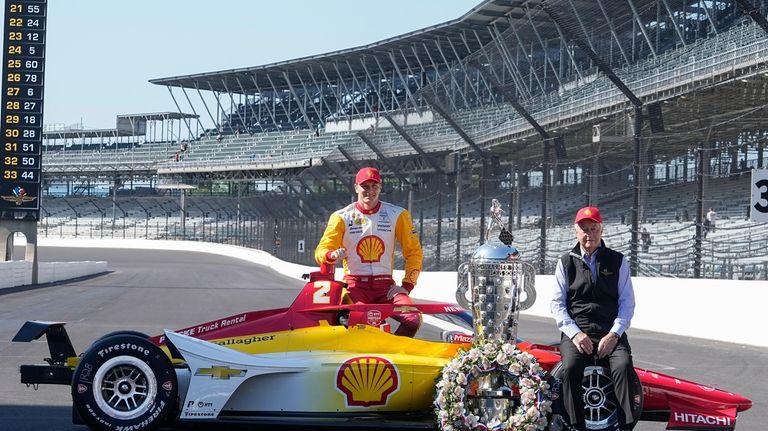 Josef Newgarden and Roger Penske pose with the Borg-Warner Trophy...