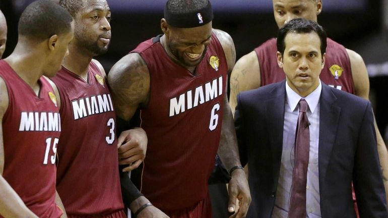 Miami Heat forward LeBron James is helped from the court...