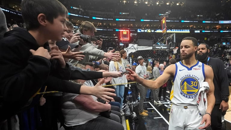 Fans reach for Golden State Warriors guard Stephen Curry (30)...