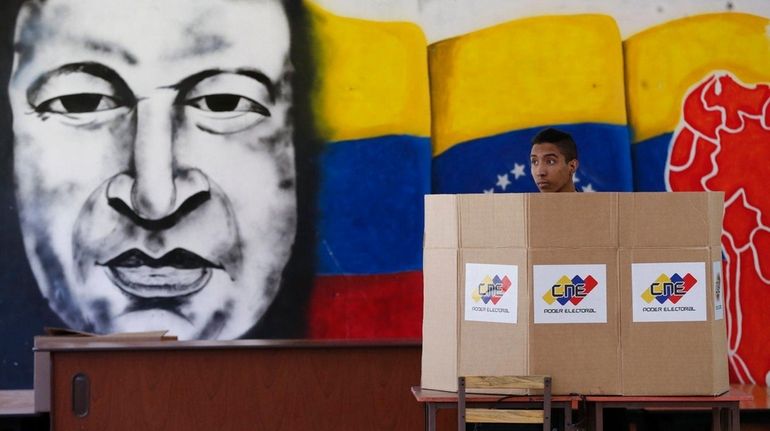 A man votes near a mural of the late Venezuelan...