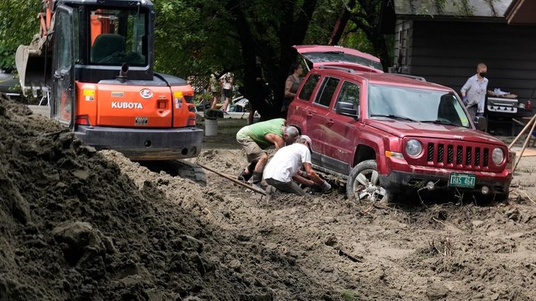 Two men dig out an SUV stuck in the mud...