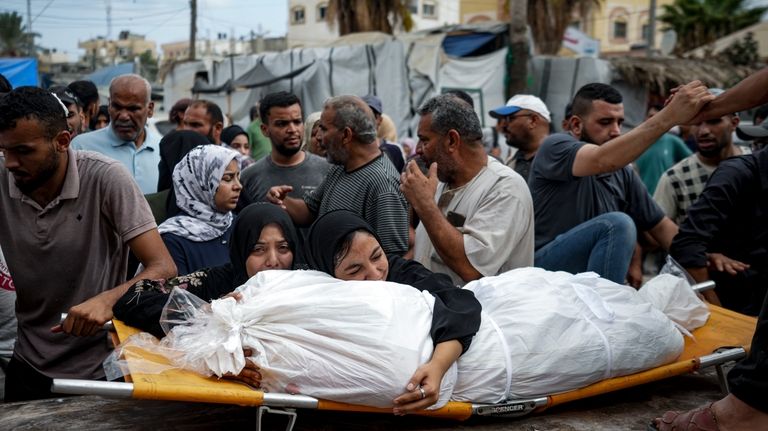 Palestinian women mourn a relative killed in the Israeli bombardment...