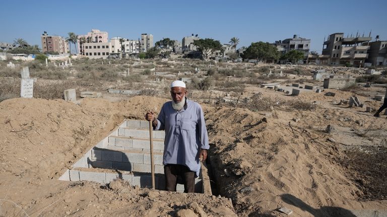 Palestinian grave digger Sa'di Baraka pauses while digging new graves...