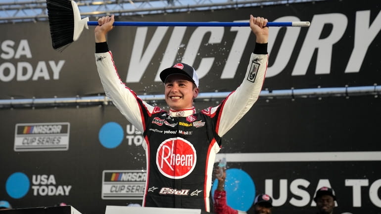 Christopher Bell hold up a broom after winning the NASCAR...