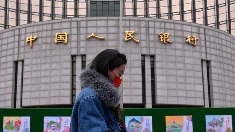 A woman walks by China's central bank, or the People's...