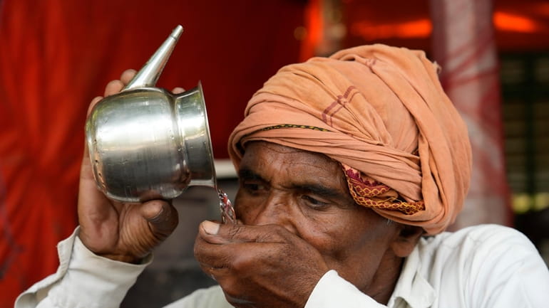 A man drinks water as severe heat grips Lucknow, India,...
