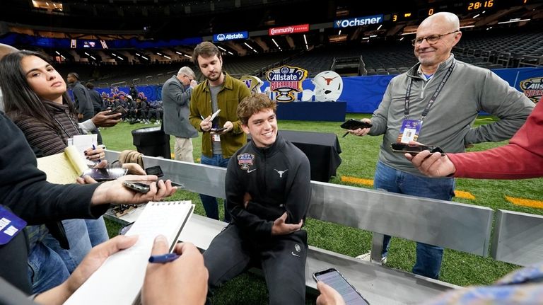 Texas quarterback Arch Manning talks to reporters during media day...