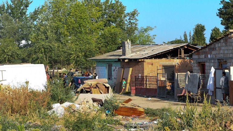 People stand in front of a small brick house after...