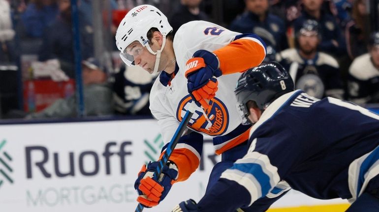 The Islanders' Oliver Wahlstrom, left, shoots the puck past the...