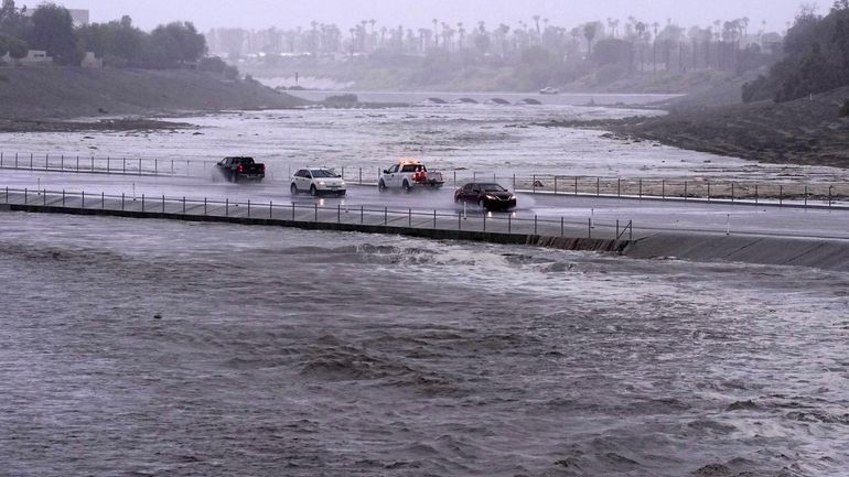 Vehicles cross over a flood control basin that has almost...