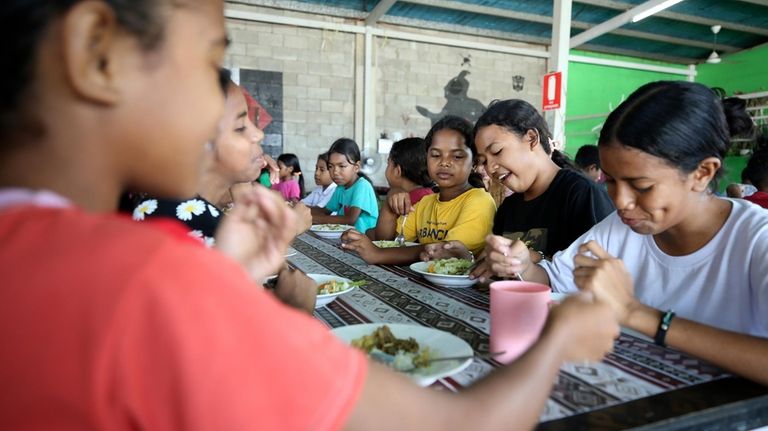 Children eat a meal distributed in schools as part of...