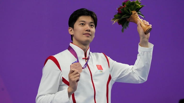 Bronze medalist Wang Shun celebrates on the podium during the...