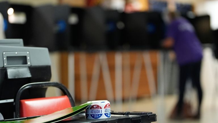 Stickers reading "I voted" rest beside a ballot scanner as...