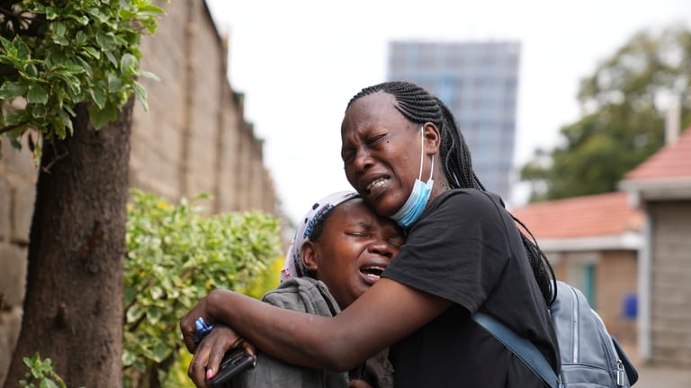 Edith Wanjiku, left, weeps after viewing the body of her...