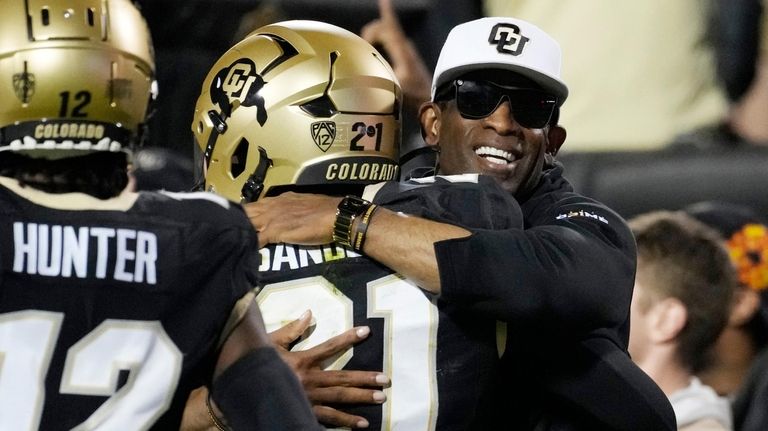 Colorado head coach Deion Sanders, right, hugs his son, safety...