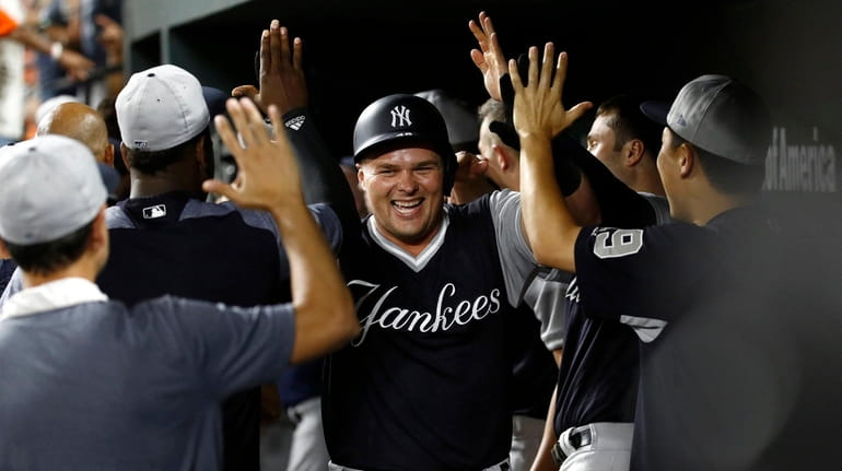 Yankees' Luke Voit, center, high-fives teammates in the dugout after...