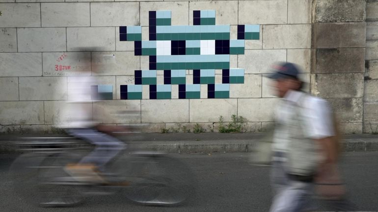 A cyclist rides in front of an Olympic-themed new mosaic...