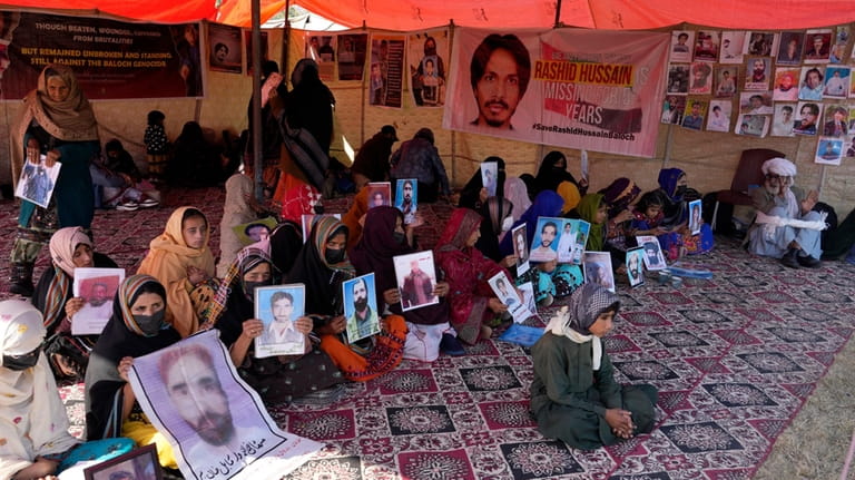 Baloch activists hold portraits of their missing family members during...