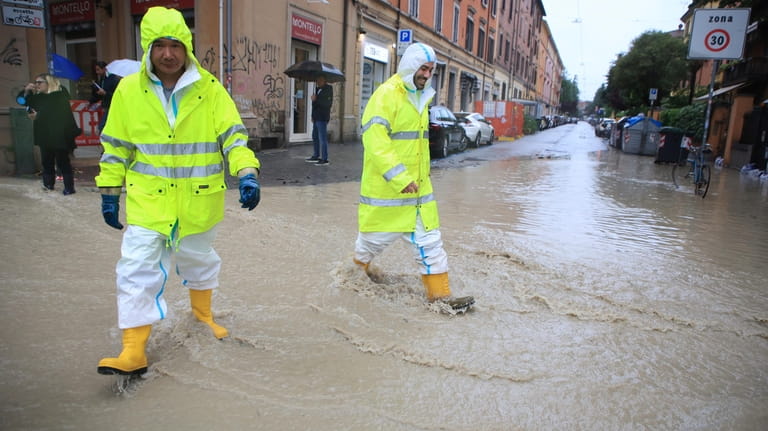 People crosses a flooded street in Bologna, Italy, Tuesday, May...