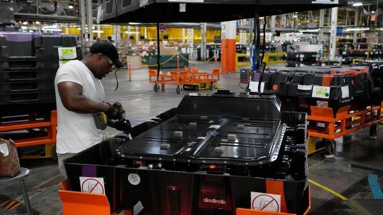 File - An assembly line worker uncrates an LG battery...