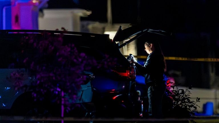 An investigator takes photographs as she examines a vehicle at...