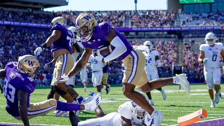 Washington wide receiver Ja'Lynn Polk, center top, falls after scoring...