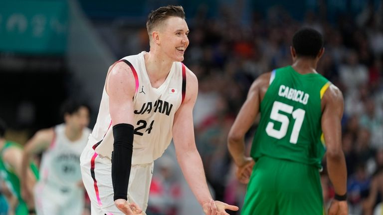 Josh Hawkinson, of Japan, celebrates after scoring a three-point basket...