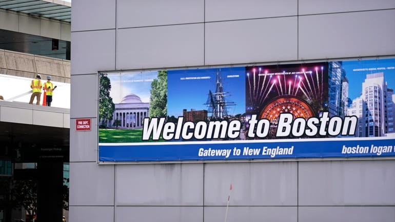 A "Welcome to Boston" sign hangs on the facade of...