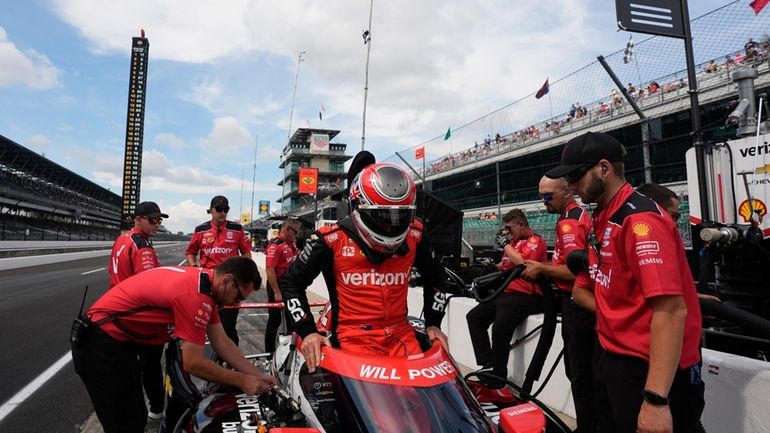 Will Power, center, of Australia, climbs into his car during...