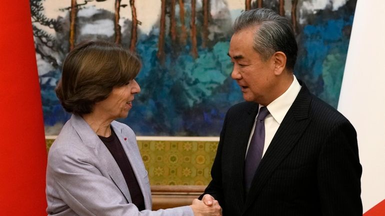 Chinese Foreign Minister Wang Yi, right, shakes hands with French...