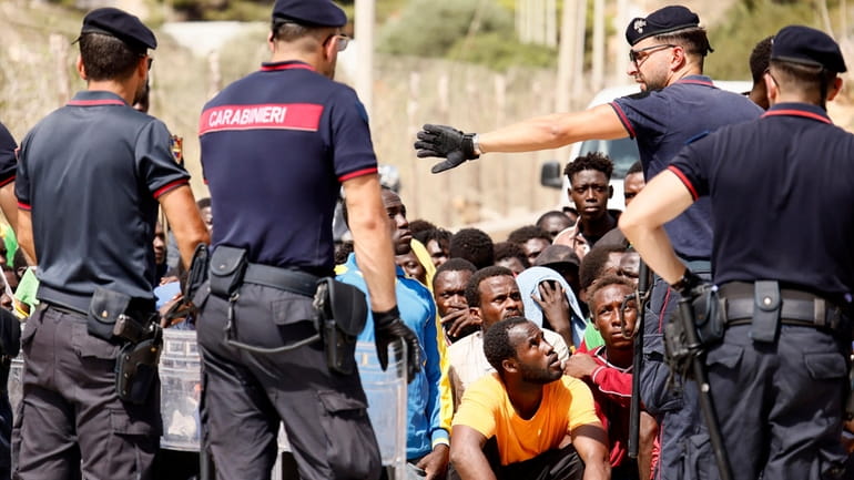 Italian carabinieri police speak to migrants protesting at a reception...