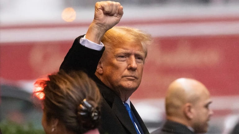 Former President Donald Trump raises his fist as he leaves...