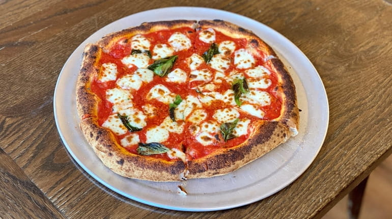 Margherita pizza is baked in a wood-fired oven at Gusto...