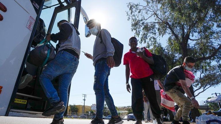 Migrants board a bus to the airport Friday, Oct. 6,...