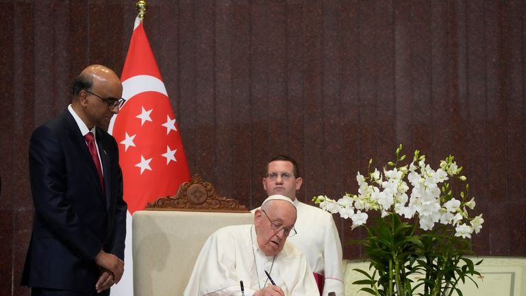 Pope Francis signs the book of honor during a welcome...