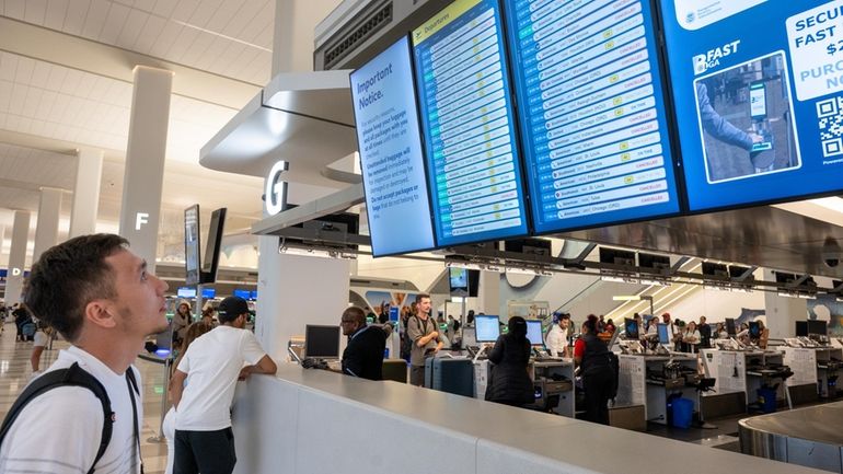 A traveler looks at the status of his flight on the...