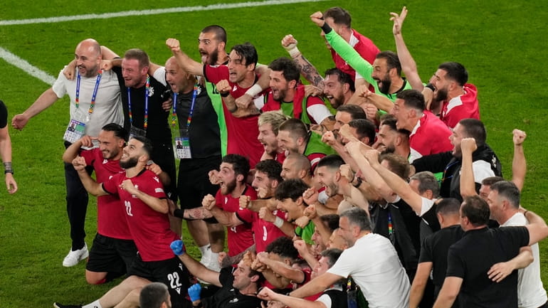 Georgia's team and staff members celebrate at the end of...