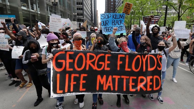 Protesters hold signs as they march during a protest over...