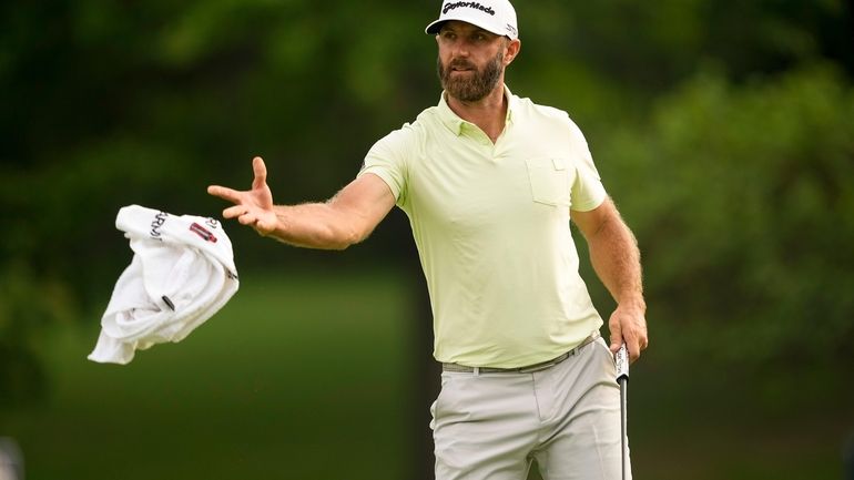 Dustin Johnson tosses his towel to his caddie on the...