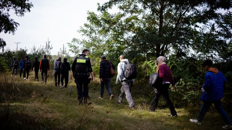 A Federal Police officer escorts a group of migrants who...