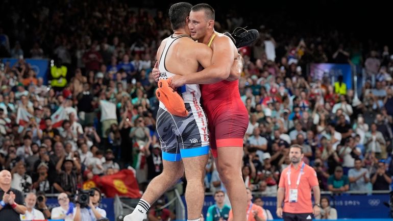 Kyrgyzstan's Aiaal Lazarev and Turkey's Taha Akgul embrace as they...