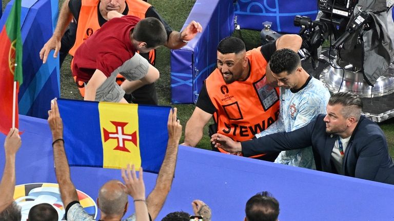 A boy crosses the barriers as Portugal's Cristiano Ronaldo, rear...