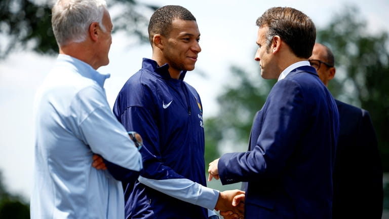 French President Emmanuel Macron, right, shakes hands with French soccer...