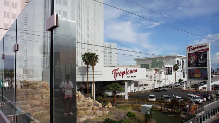 A person, reflected in glass, walks near the Tropicana Las...