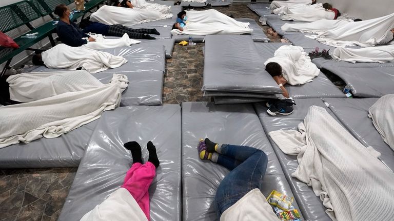 Women wait in a Border Patrol holding facility Friday, Dec....