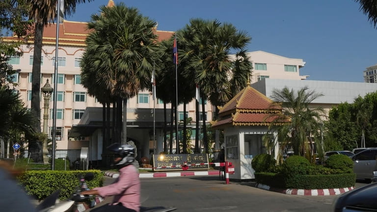 People drive their vehicles past a main entrance of Phnom...
